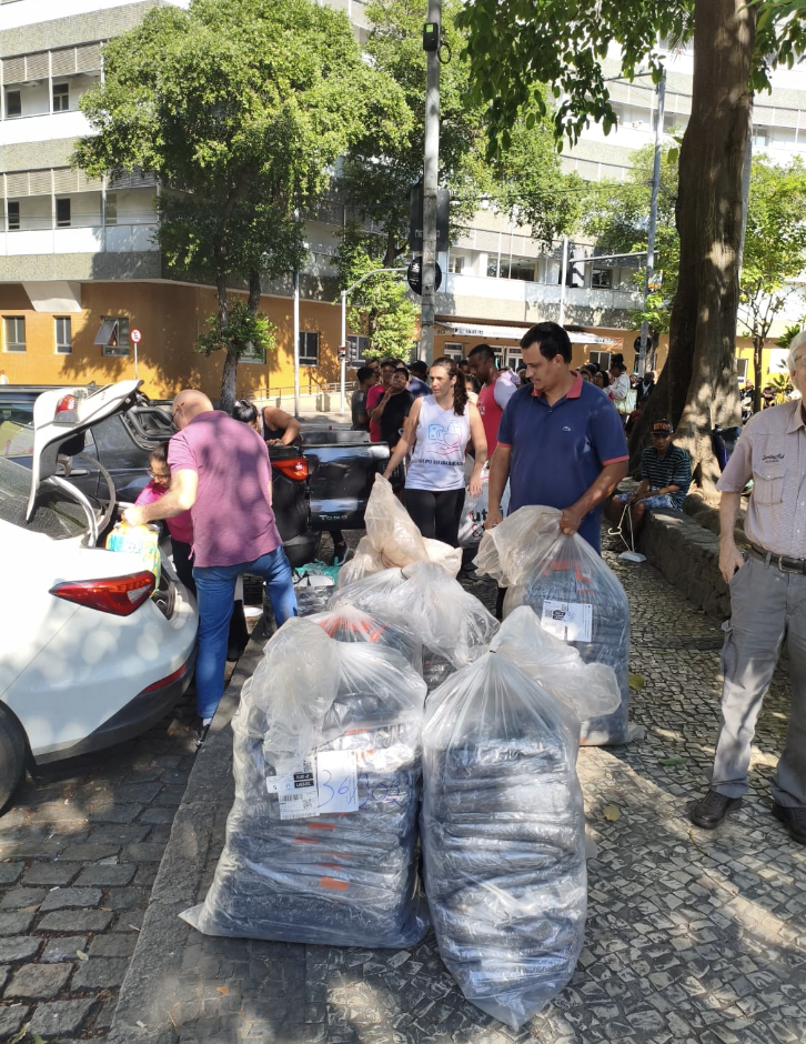 Voluntários entregando sacolas de doações na rua