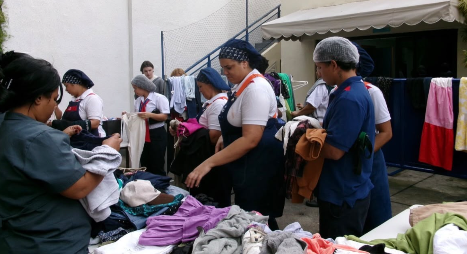 Funcionárias da creche organizando roupas do bazar
